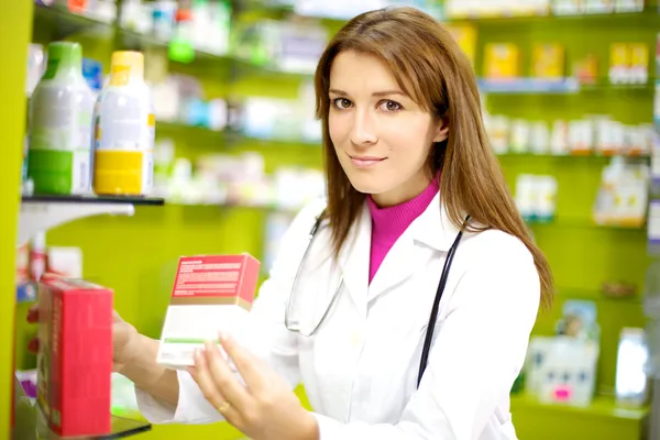 Smiling female doctor in pharmacy with medicine — Stock Photo, Image