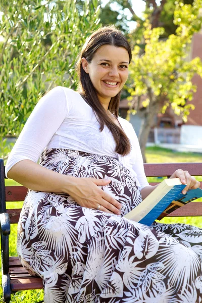 Beautiful pregnant woman with book smiling — Stock Photo, Image