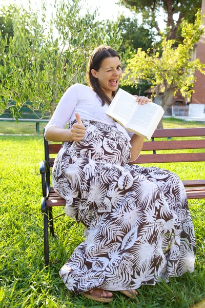 Těhotná žena s úsměvem a kniha — Stock fotografie