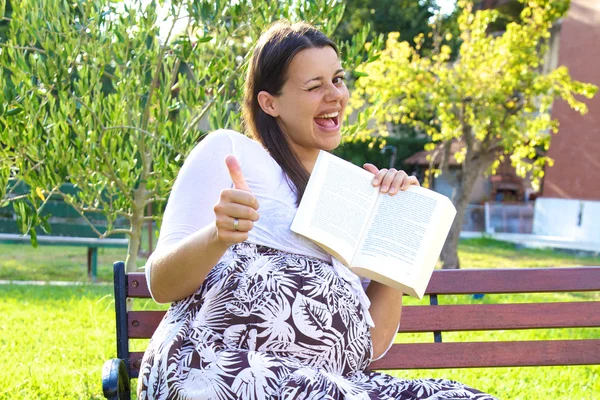 Kitap başparmak ile hamile kadın — Stok fotoğraf