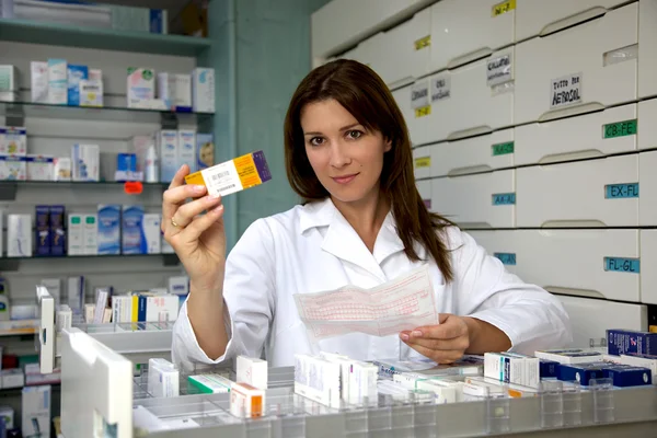 Красивая аптекарша показывает лекарства — стоковое фото
