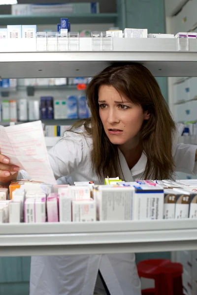 Женщина работает в аптеке ищет рецепт — стоковое фото