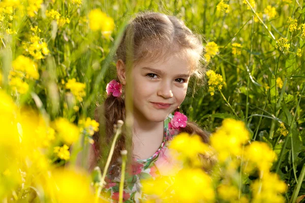 Little girl sitting in the grass and flowers — Stock Photo, Image