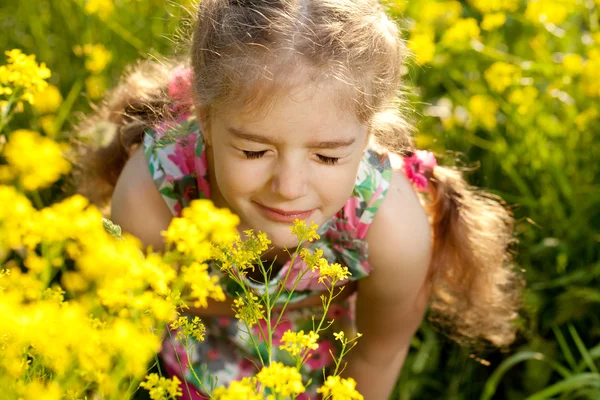 小さな金髪の少女は、花の香りを吸い込む — ストック写真