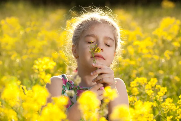 Kleines Mädchen genießt den Duft von Blumen — Stockfoto