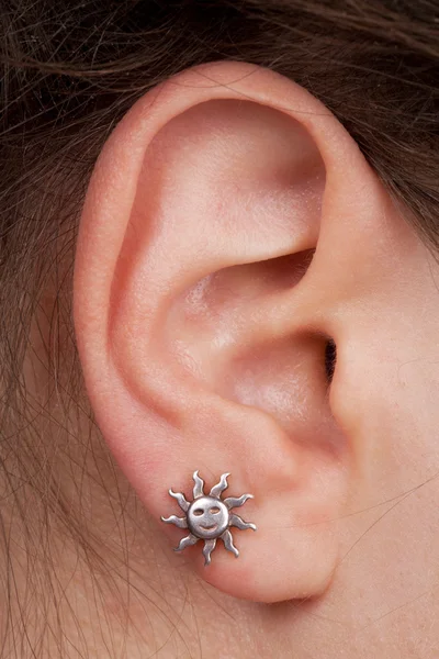 Женское ухо с сережкой — стоковое фото