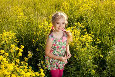 Funny little girl among yellow wildflowers clipart