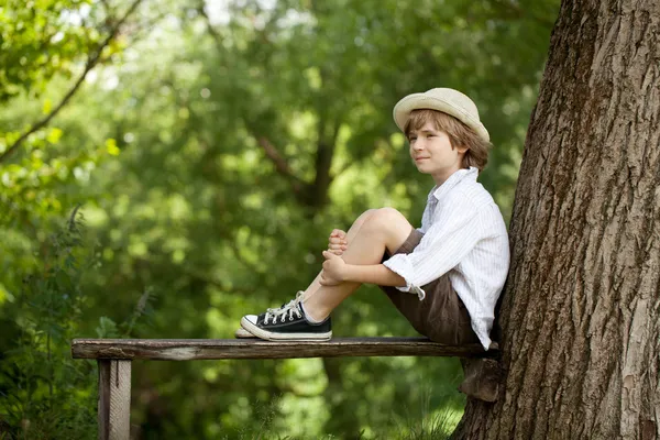 El chico se sienta en un banco de madera — Foto de Stock