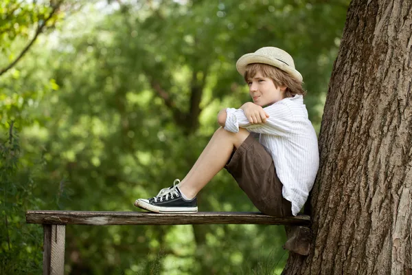 男孩坐在一张长凳上 — 图库照片