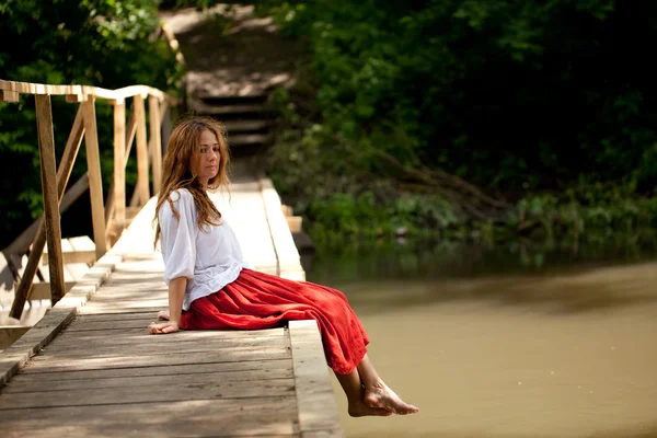 Ung kvinna sitter på bron — Stockfoto