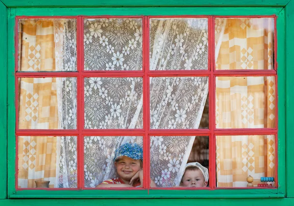 Twee kinderen kijken uit het raam — Stockfoto