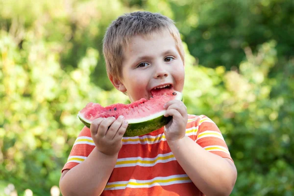 Boy bites off a piece of watermelon — Stock Photo, Image