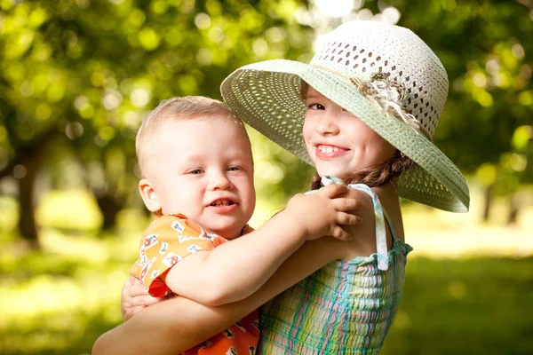 Mädchen im Hut hält die Arme seines Bruders — Stockfoto