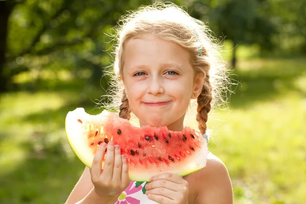 Beautiful blonde girl with pigtails eating a watermelon — Stock Photo, Image