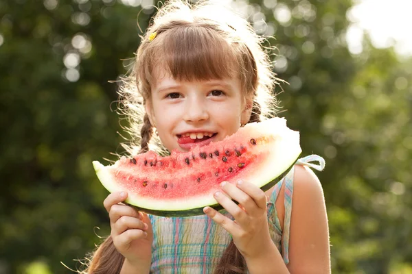 Funny little girl with pigtails eating a watermelon — Stock Photo, Image