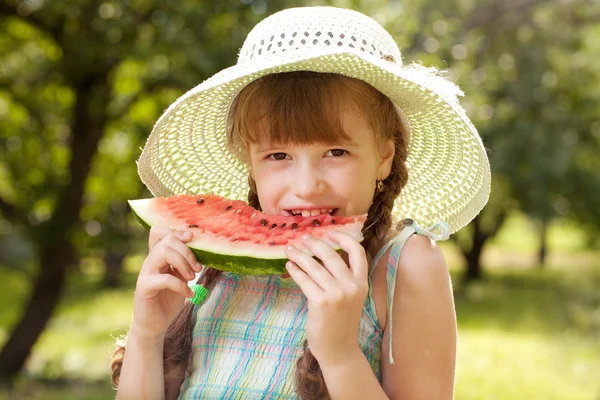 Chica en sombrero comiendo una sandía roja — Foto de Stock