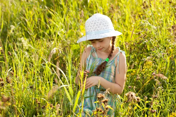 Klein meisje onder het gras — Stockfoto