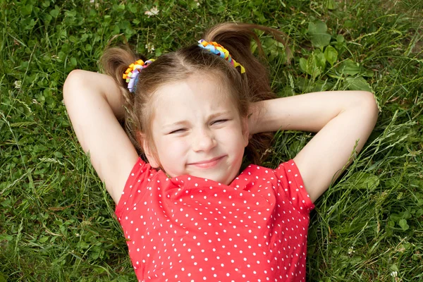 Dívka s copánky, ležící na trávě — Stock fotografie