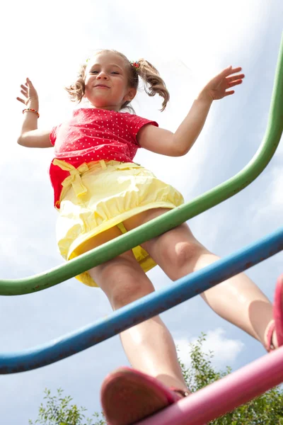 Menina com tranças joga no parque infantil — Fotografia de Stock