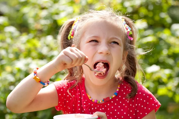 Girl with pigtails eats with relish ice cream — Stock Photo, Image