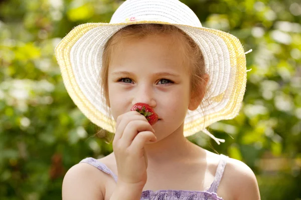 Menina no chapéu cheira a morangos frescos — Fotografia de Stock