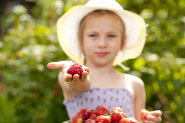 Girl in the hat handed to us strawberries — Stock Photo, Image