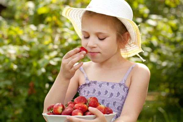 Menina no chapéu respira cheiro de morangos — Fotografia de Stock