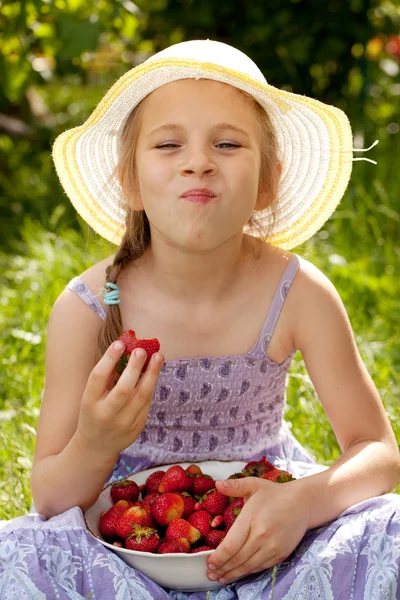 Menina goza de um morango maduro — Fotografia de Stock