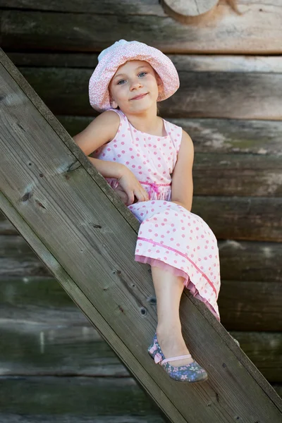 Menina engraçada no panamá senta-se em uma escada — Fotografia de Stock