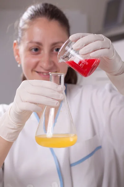 Mulher examinar garrafas coloridas encher com produtos químicos — Fotografia de Stock