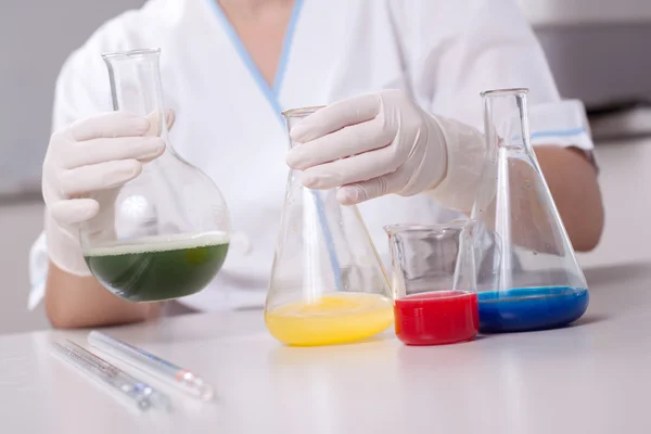 Mujer examinar colorido botellas llenar con productos químicos —  Fotos de Stock