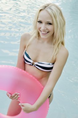 Pretty young woman enjoying summer in the pool clipart