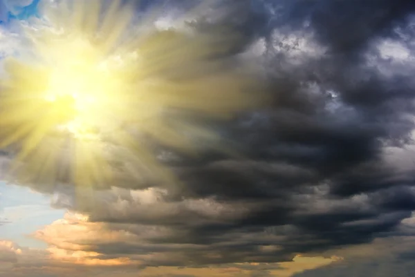Sun pushing through a dark dense clouds — Stock Photo, Image