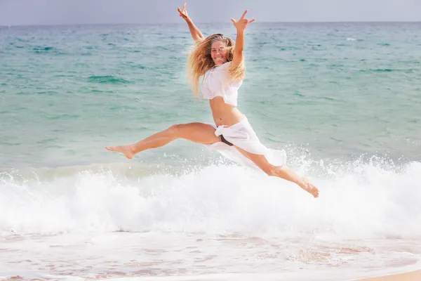 Pretty Fit Woman Jumping out of the water on the Beach — Stock Photo, Image