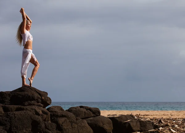 Gorgeous woman stretching up tall on lava rocks — Stock Photo, Image