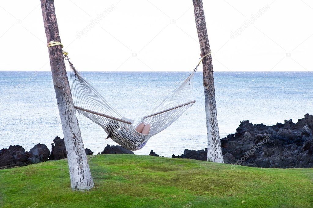 Woman curled up in a hammock swing