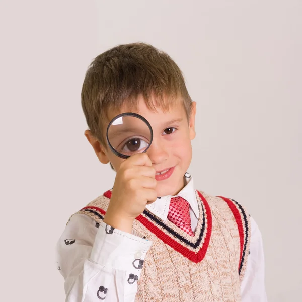 Primo piano di un ragazzo dagli occhi verdi che guarda attraverso la lente d'ingrandimento — Foto Stock