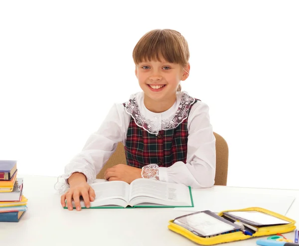 Porträtt av en y glad liten skolflicka vid skrivbordet över vita — Stockfoto