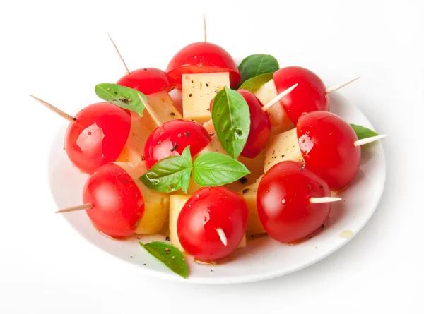 Tranches de tomate et fromage décorées avec des feuilles de basilic sur une assiette et fond blanc — Photo