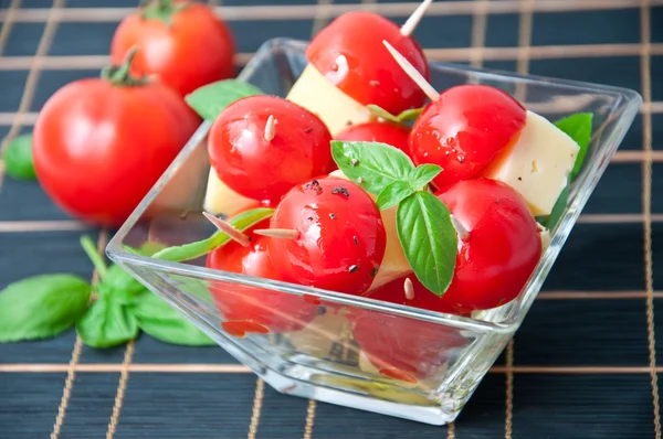 Rodajas de tomate y queso decoradas con hojas de albahaca en un plato —  Fotos de Stock