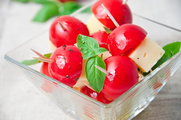Plátky rajčete a sýrem zdobený bazalkové listy na talíř a bílé pozadí — Stock fotografie