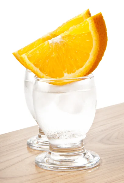 Un bicchiere di acqua ghiacciata o una bevanda vodka con una fetta di arancia — Foto Stock