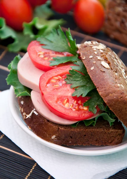 Φέτες ζαμπόν σάντουιτς με ντομάτες σε μια μικτή σπόρων ψωμί — Φωτογραφία Αρχείου