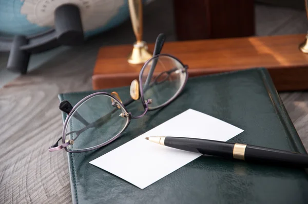 O caderno e os óculos com a caneta repousam sobre um fundo cinzento — Fotografia de Stock