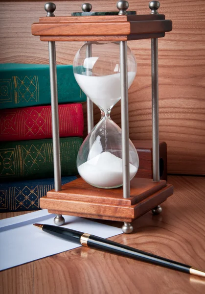 Přesýpací hodiny a kniha na dřevěný stůl — Stock fotografie