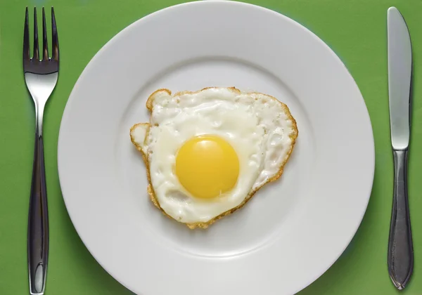 Huevo frito en un plato con cubiertos —  Fotos de Stock