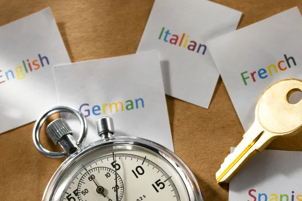 Kaarten met verschillende talen, stopwatch en sleutel — Stockfoto
