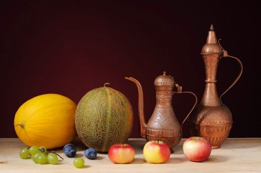 Metal jug, melons and fruits on the table clipart