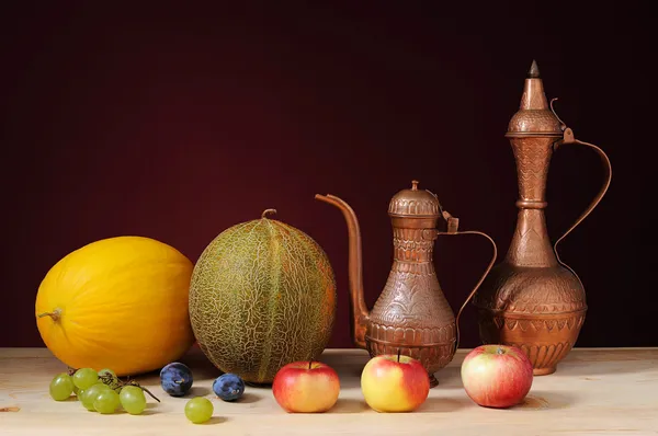 Metal jug, melons and fruits on the table — Stock Photo, Image