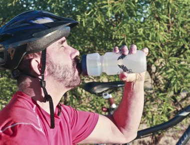 A Bicyclist Stops for a Water Break clipart